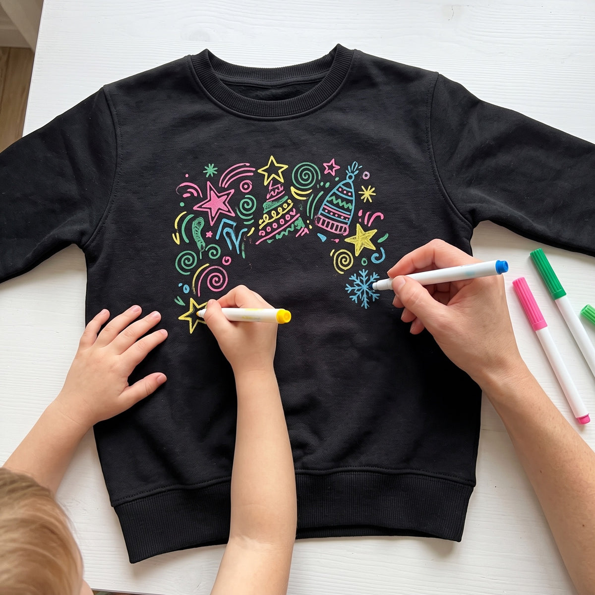 Parent and child drawing on a sweatshirt with glow markers